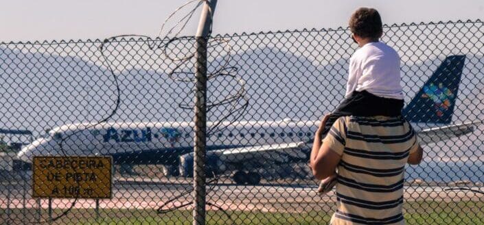 Man carrying his child overlooking an airplane