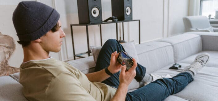 Man sitting on couch playing mobile games