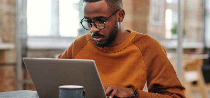 A man with glasses working on laptop