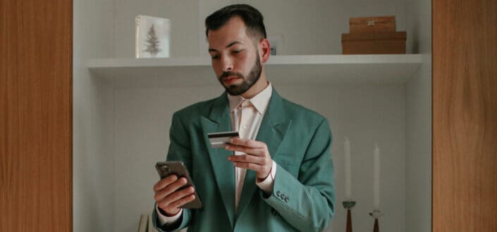 suited man holding credit card and phone