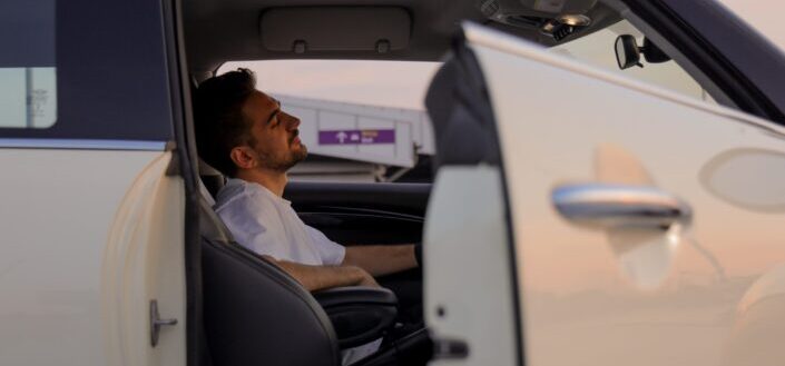 Man Lying In Car Seat At Sunset