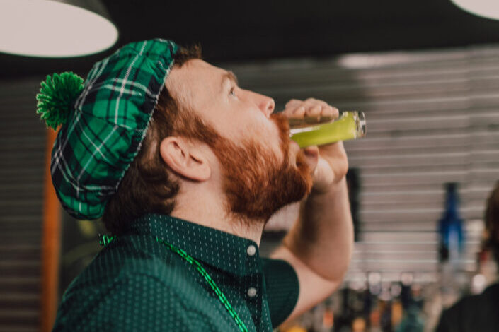 Man wearing green clothes drinking a shot
