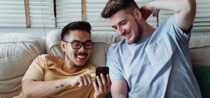 Men laughing while looking at the screen of a cellphone
