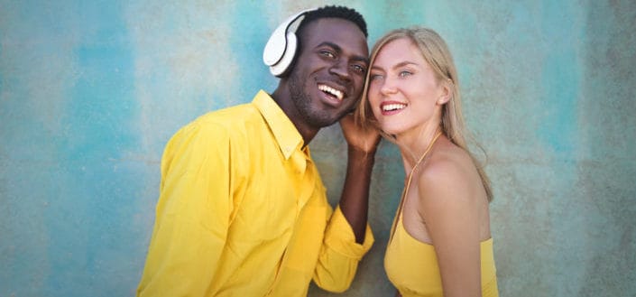 woman trying to hear the sound from a man's headphones
