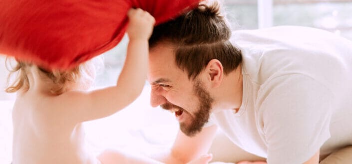 Father playing pillow fight with son