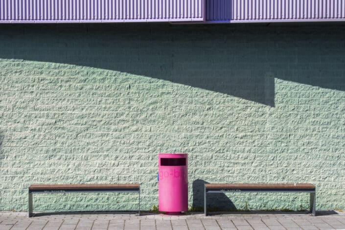 Pink garbage bin between two benches