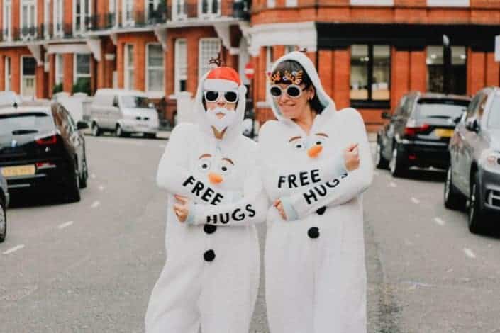 two people wearing white snowman overalls with free hugs print
