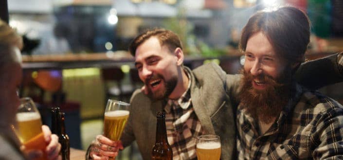 Male friends laughing while drinking beers.