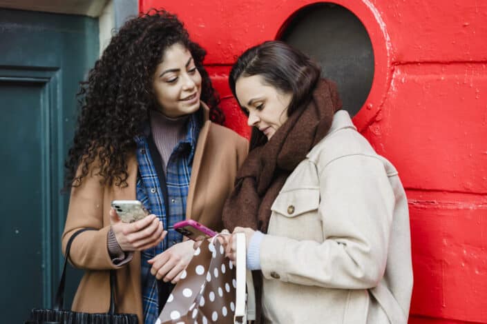 young ladies surfing smartphones on street 