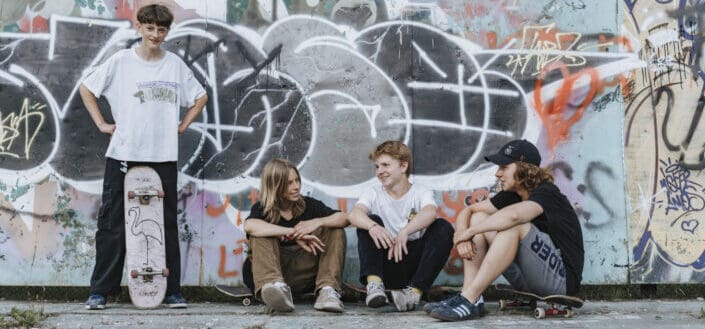 Teenagers Sitting on Concrete Pavement Near Wall