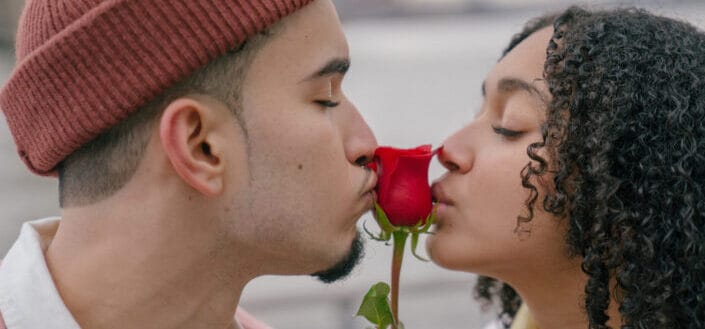 Tender hispanic couple kissing rose on waterfront
