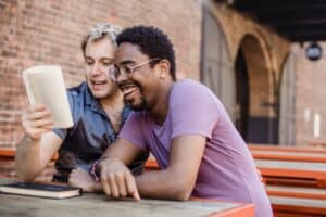 two friends laughing at something they're reading - bad knock knock jokes