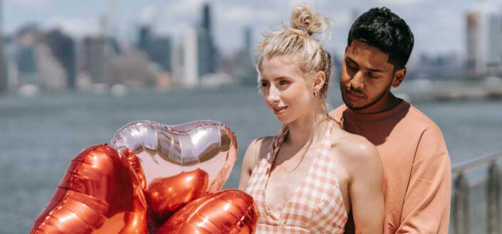 Man Hugging a Woman Holding Heart Balloons