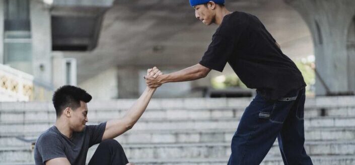 man helping friend to get up from ground