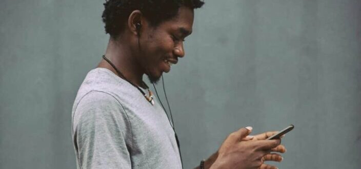 man listening to his phone with earbuds