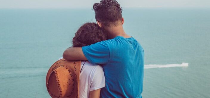 Couple hugging while looking at the sea