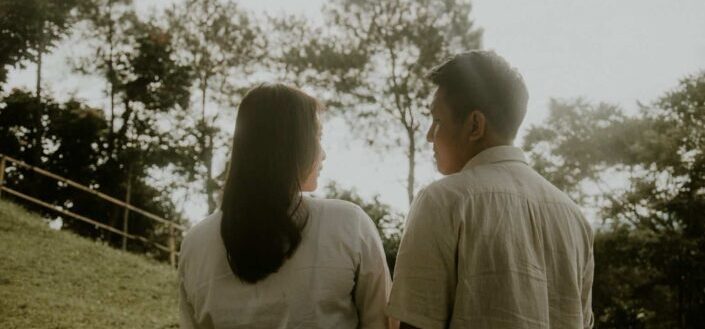 man and woman standing near green field