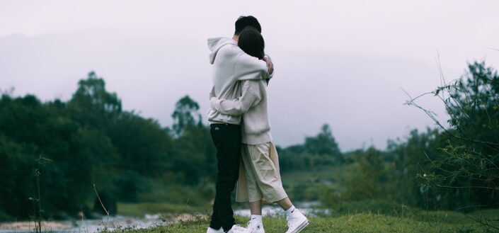 Couple hugging while standing beside a river