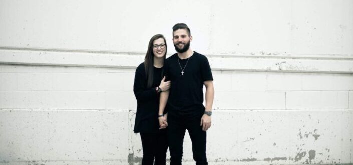 couple standing in front of white concrete wall