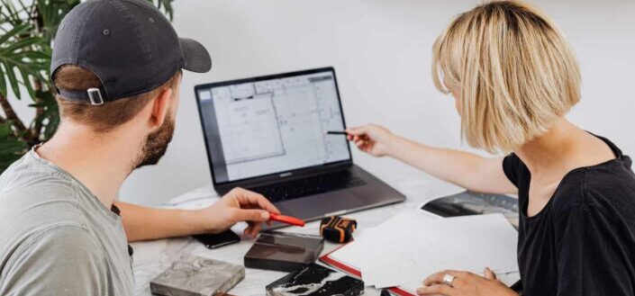 Coworkers pointing at a laptop and tiles