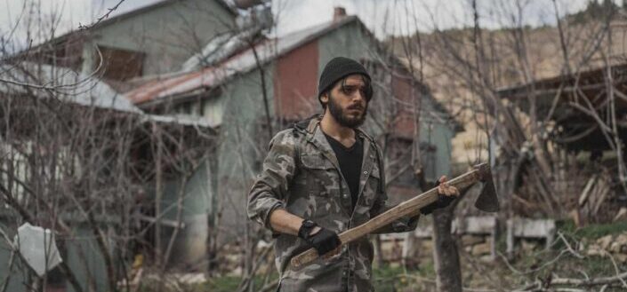 Man in camouflage jacket holding wooden axe