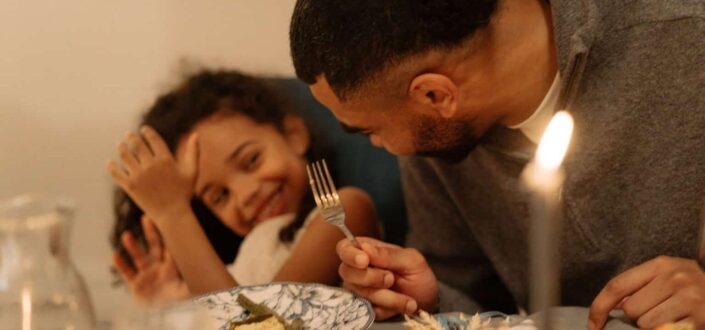Man smiling at child while eating dinner