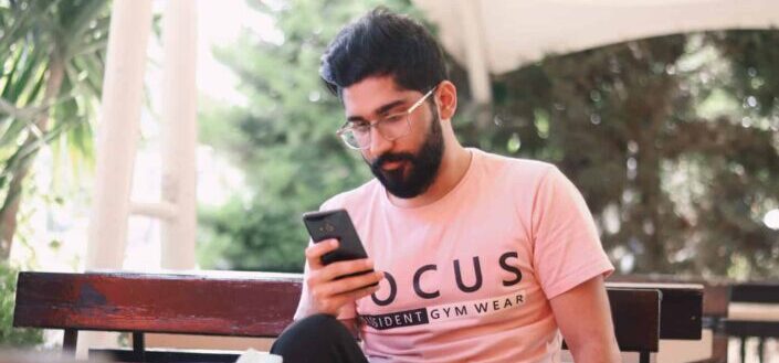 man in pink t-shirt using phone