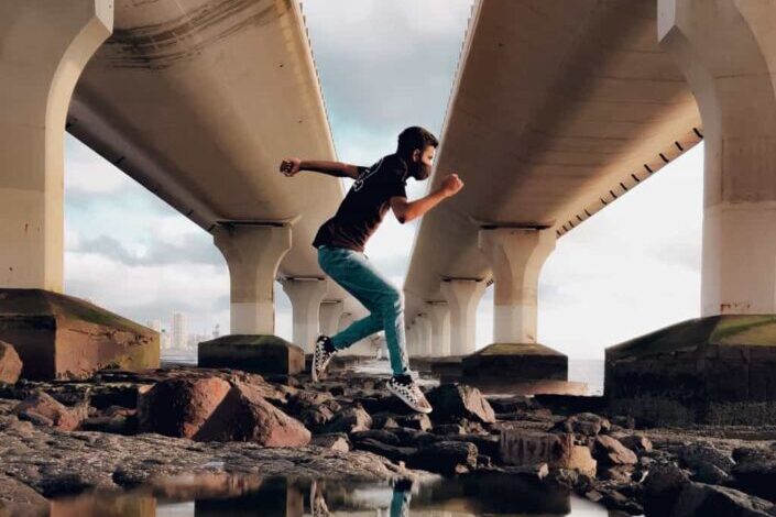 Man walking on stones under a bridge