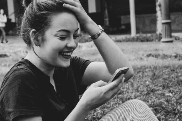 woman smiling while using phone