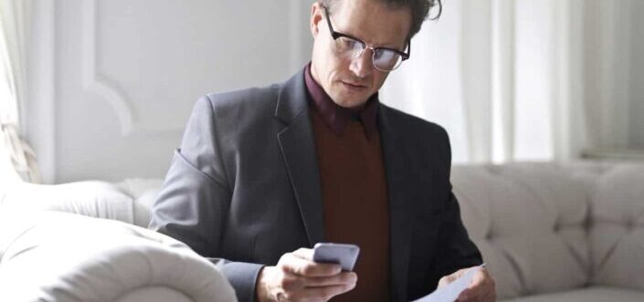 Man on White Sofa Using a Phone