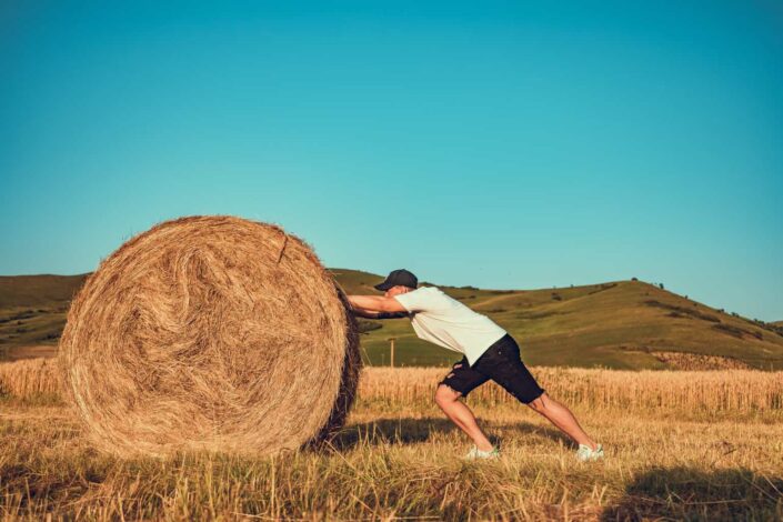 man pushing hay bale