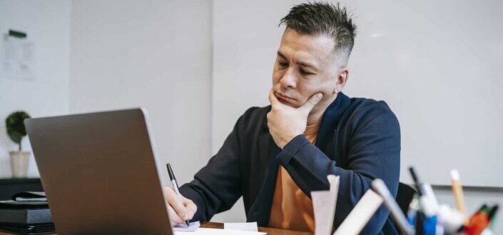 man thinking while writing