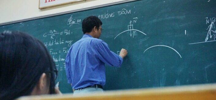 Physics teacher writing on blackboard
