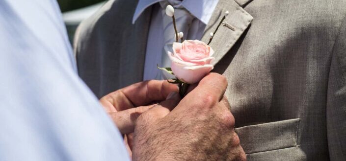 man pinning a pink rose 
