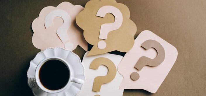 Question marks on paper crafts beside coffee drink