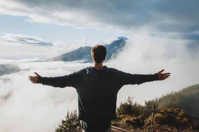 man with outstretched arms facing the cliff - Rise And Grind Quotes