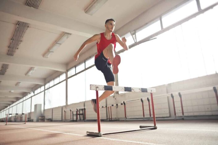 Strong young sportsman jumping over barrier