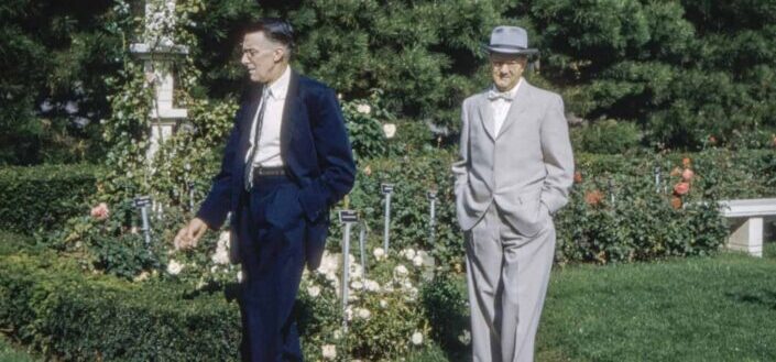 two gentlemen walking near flowers