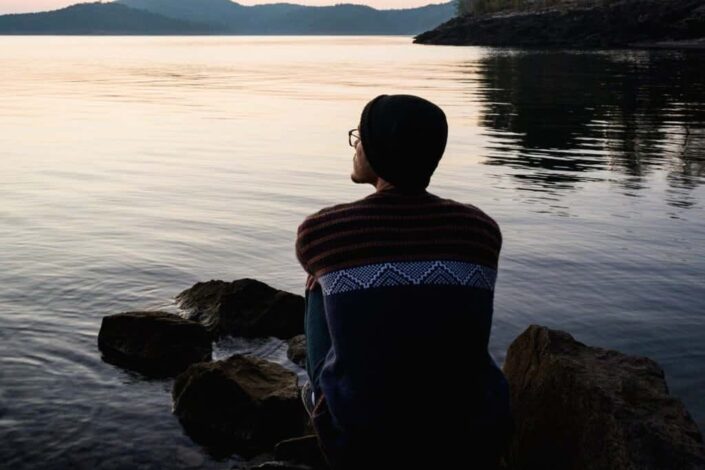 man gazing at sunrise surrounded by water