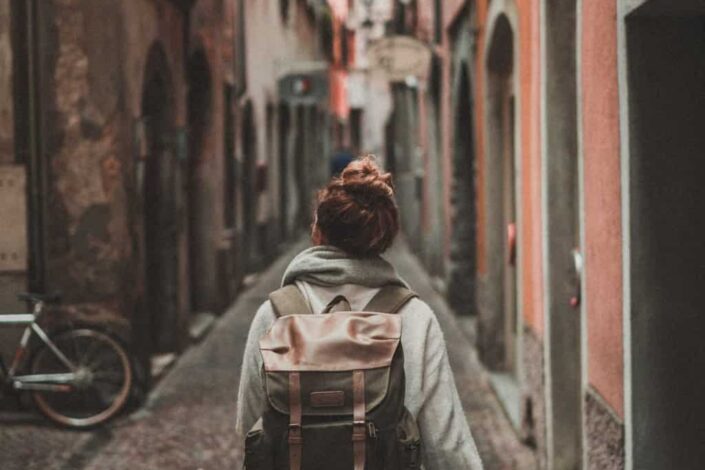 woman walking on street surrounded by buildings