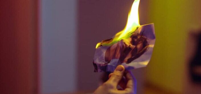 A Hand Holding a Burning Photo