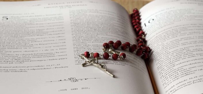 Rosary on top of opened bible book