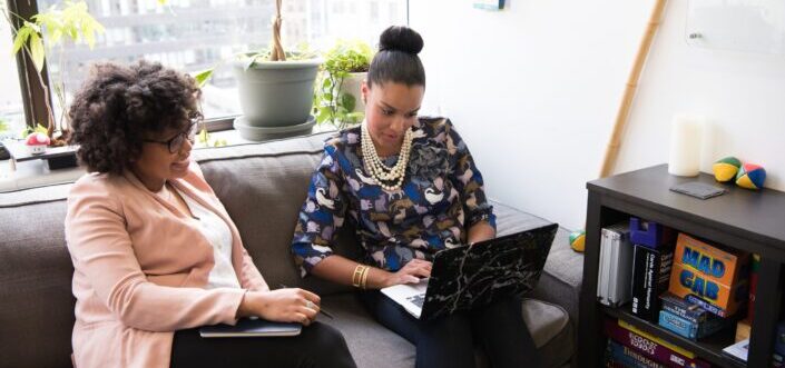 two woman siting on sofa inside room