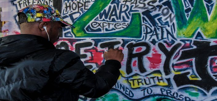 man spraying graffiti on wall